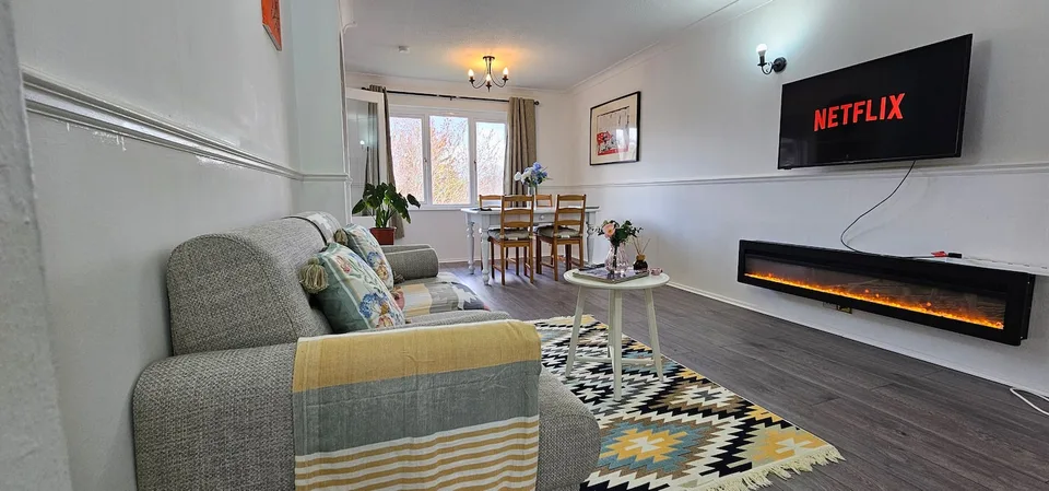 Living room with sofa, television and a dining table by the window
