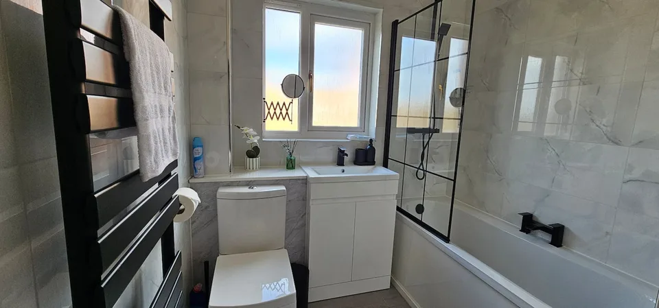 Bathroom with a bath, shower screen and window